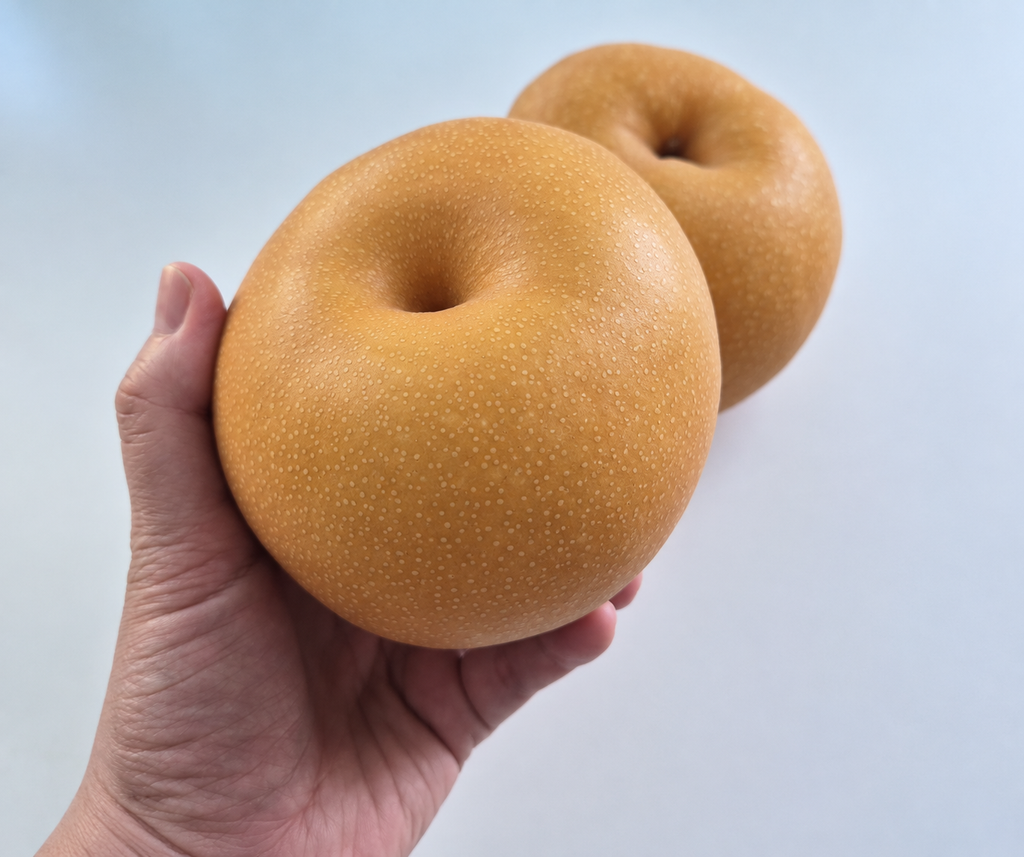 A round Korean pear with its variety and origin label in a Seoul fruit shop