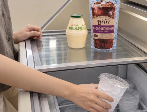A shopper preparing a pouch drink with an ice cup at a convenience store
